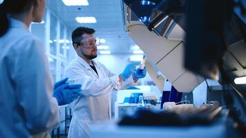 Team of Medical Research Scientists Work on a New Generation Disease Cure. They use Microscope, Test Tubes, Micropipette and Writing Down Analysis Results. Laboratory Looks Busy, Blue and Modern photo