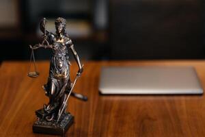 Golden lady justice statue is displayed on a wooden desk in a law office, symbolizing justice, fairness, and the legal system. Statue of Themis with a pair of scales of justice. Banner advertising photo
