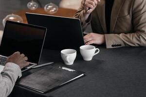 Close-up shot of business professionals discussing financial marketing data while sitting at a table with project documents during a business lunch. Banner photo
