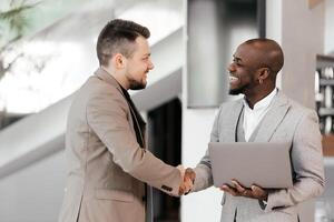 African Manager, business men in meeting with laptop, coaching or learning in creative startup. Team, leader and discussion for brainstorming ideas, project update for event planning. Handshake, deal photo