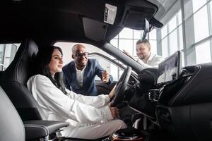 Happy caucasian woman is sitting in the drivers seat of a grey sedan. New car from a dealership representative. The concept of test drive, buying an electric car or renting photo