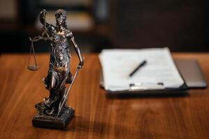 Golden lady justice statue is displayed on a wooden desk in a law office, symbolizing justice, fairness, and the legal system. Statue of Themis with a pair of scales of justice. Free copy space photo