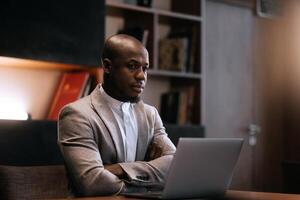 Stress, burnout and business black man at night working on project, report and strategy deadline. Headache, mental health and male in dark office frustrated, tired and work problem on computer photo