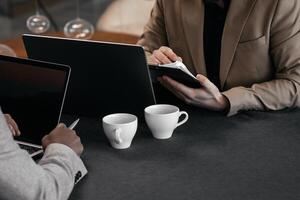Close-up shot of business professionals discussing financial marketing data while sitting at a table with project documents during a business lunch. Copy space photo