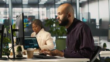 Arab man in office reviewing financial graphs, analyzing key performance indicators. Middle Eastern employee in workspace looking over data trends and strategic insights, camera A video