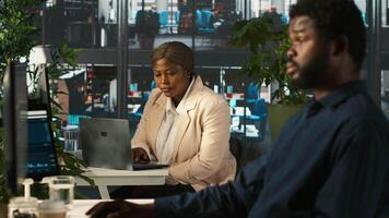 Employee in office showing revenue figures on laptop to manager. Accountant presenting company statistical numbers on notebook to supervisor after finishing job tasks, camera A video