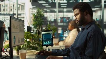 Close up of worker in office using landline phone to talk with customer. African american employee at work discussing with business partner during call, analyzing performance metrics, camera B video