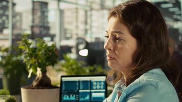 Worker in office falling asleep at computer desk while analyzing business performance metrics. Exhausted woman dozing off while reviewing financial charts at work, camera B video