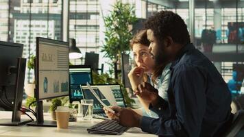 Manager at office desk next to accountant checking financial figures on documents, doing reports. Team leader and man working together crosschecking data on paperwork files, camera B video
