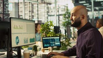 Startup staff member working to hit key performance targets for revenue, profitability and operational efficiency. Employee at computer desk doing research analysis, camera B close up video