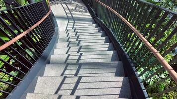 Winding staircase casting shadows in sunny park setting video