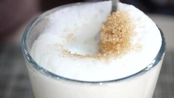 Sugaring frothy drink at a cafe during afternoon video