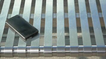 Smartphone resting on metallic bench, lost smart phone concept video