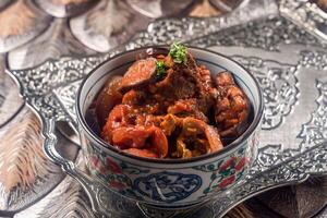 Stew Eggplant with meat served in a decorative bowl with rich tomato sauce isolated on wooden table side view of gourmet Middle Eastern stew photo