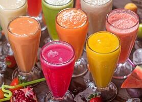assorted colorful fruit juices in tall glasses incliding Strawberry, Mango, orange, Pomegranate, Watermelon, Lemon, lemon mint, and Banana Milkshake top view of refreshing collection beverages photo