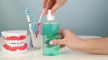 Hands demonstrating mouthwash use next to toothbrushes and dentures in a bathroom setting video