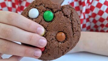 Hands holding colorful chocolate chip cookie with red checkered background video