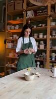 Female potter check molded clay mug for strength, touching handle in workshop. Craftsmanship skills video