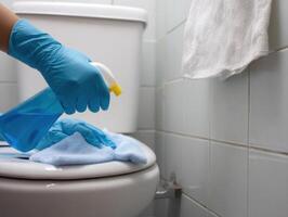 Cleaning toilet with blue spray and towel, showcasing hand in blue glove. scene emphasizes hygiene and cleanliness in bathroom setting photo
