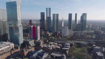Aerial view of Manchester, UK, showcasing skyscrapers like Beetham Tower, train tracks, a railway bridge, and a colorful building under clear skies. video