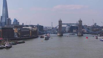 Aerial view of Tower Bridge over the River Thames with boats in motion, modern skyscrapers in the background, and vibrant riverside scenery. video