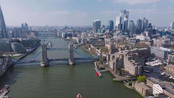 Aerial view of Tower Bridge over the River Thames with The Shard in the background. Boats, including a red speedboat, move along the river. video