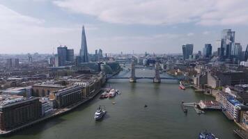 Aerial view of Tower Bridge spanning the River Thames, with the Gherkin and skyscrapers in the background. Boats move along the river under a cloudy sky. video