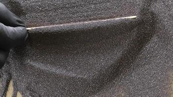 behandschuhte Hand mit Stock zu Niveau dunkel Diamant Schleifmittel Pulver über Oberfläche, Makro Nahansicht zeigen Textur Steuerung im Synthetik Mahlen Material Vorbereitung video