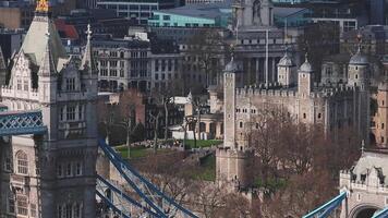 Aerial view of the Tower of London and Tower Bridge, showcasing medieval architecture alongside modern office buildings in a smooth panning motion. video
