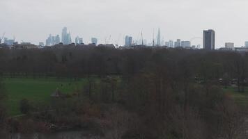 Aerial view of London featuring the Shard, London Eye, and City skyscrapers. A large park with pathways and trees is visible under an overcast sky. video