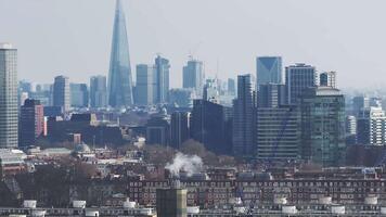 Aerial view of London showcasing the Shard, Canary Wharf, and the River Thames. The scene includes a hazy skyline and ongoing urban development. video