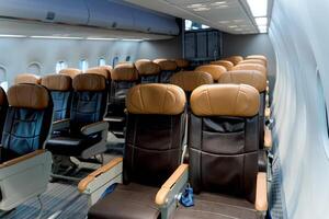 Interior view of modern commercial airplane cabin with rows of empty leather seats and window-side lighting, showcasing comfortable air travel arrangement photo