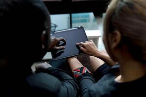 Close-up of two people collaborating on a digital tablet, teamwork and discussion concept in a modern workspace with touch screen technology photo