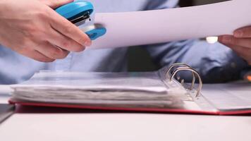 Office worker stapling documents to a folder using a blue stapler video