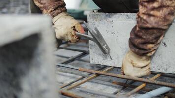 Worker securing formwork on rebar grid with hammer video