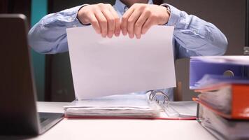 Office worker tearing paper document, contract in half at desk with binders and laptop video