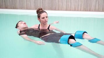 Therapeutic water exercise relaxation and support techniques demonstrated in aqua therapy session. video