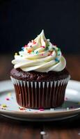 A chocolate cupcake with white frosting and sprinkles photo