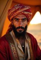 A middle eastern man, 35 years old, with black beard and mustache, wearing a turban and a red robe in the desert photo