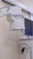 C-Arm fluoroscopy machine standing in the modern surgery room. Operational table with lung ventilation system standing nearby video