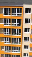 Fassade von neu gebaut Wolkenkratzer. modern Gebäude mit hell Wände im das Stadt. hoch angehoben Gebäude mit groß Fenster und Balkone. Vorderseite Sicht. Vertikale video