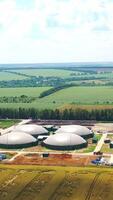 Modern farm for biogas production on field. Innovative factory among beautiful nature. Special round reservoirs for methane-containing gas. Vertical video