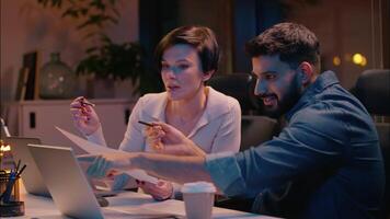 Multiracial teamwork Indian man Caucasian woman business partners co-workers colleagues talking at dark night evening office girl guy businessman businesswoman designers discuss project startup laptop video