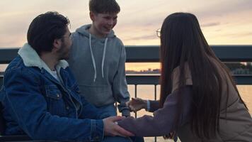 Father, injured and seated in wheelchair, is accompanied by his family as they enjoy socializing on cold autumn day. All of them smiling and having great time, enjoying each other's company and outdoors. video
