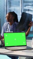 Vertical Experienced physician doing checkup routine with patient next to chroma key screen, discussing about medicine and wellness. Man using health insurance for consultation with medic. Camera B. video