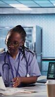 Vertical Medical assistant consulting couple of patients about test results and MRI scans, reviewing records to create the diagnostic report. Patient care management in a medical cabinet. Camera A. video