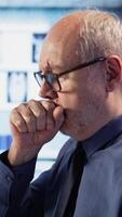 Vertical Old man in wheelchair coughing and dealing with a respiratory problem, flu symptoms at checkup with medical expert. Patient with disability suffering from asthma or throat infection. Camera A. video