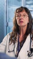 Vertical Healthcare specialist sharing medical expertise and reading the MRI scans results with male patient, reviewing x ray reports for the correct diagnostic. Expert discuss treatment plans. Camera B. video
