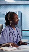Vertical Medical assistant consulting senior patients about test results and MRI scans, reviewing hospital records to create the diagnostic report. Patient care management in a medical clinic. Camera A. video