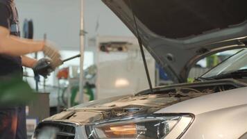 Auto mechanic inspecting engine compartment under raised hood in workshop. video